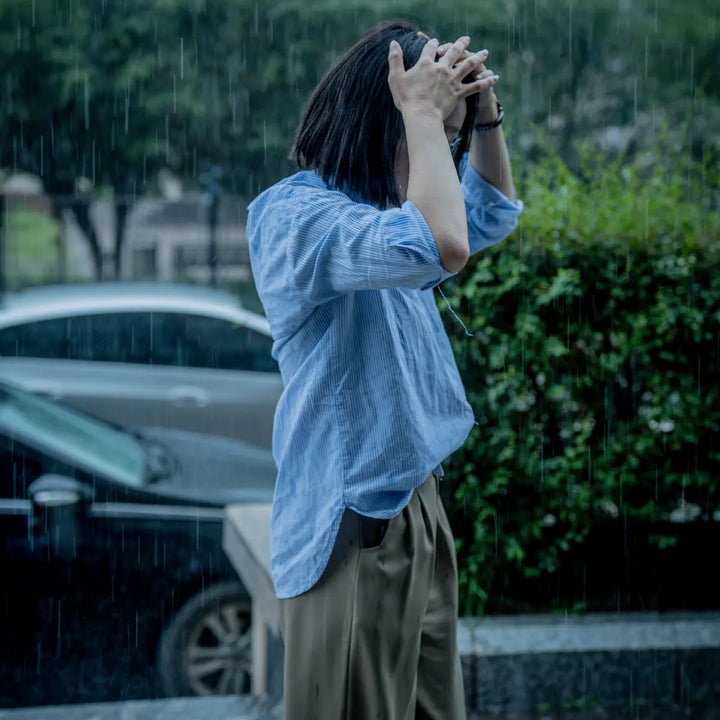 Woman standing in the rain with her hands on her head, illustrating an overwhelming stress response