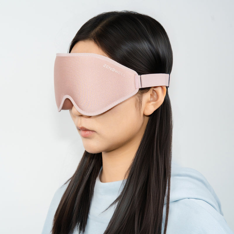 A person wearing a pink  ZenoWell sleep mask, with the logo visible, the product from the side view.